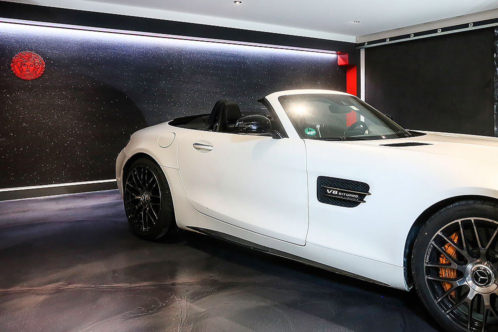 Ein weißes Mercedes-Cabriolet mit offenem Dach steht in einer privaten Parkgarage, deren Boden und Wände in Schwarz veredelt worden sind.