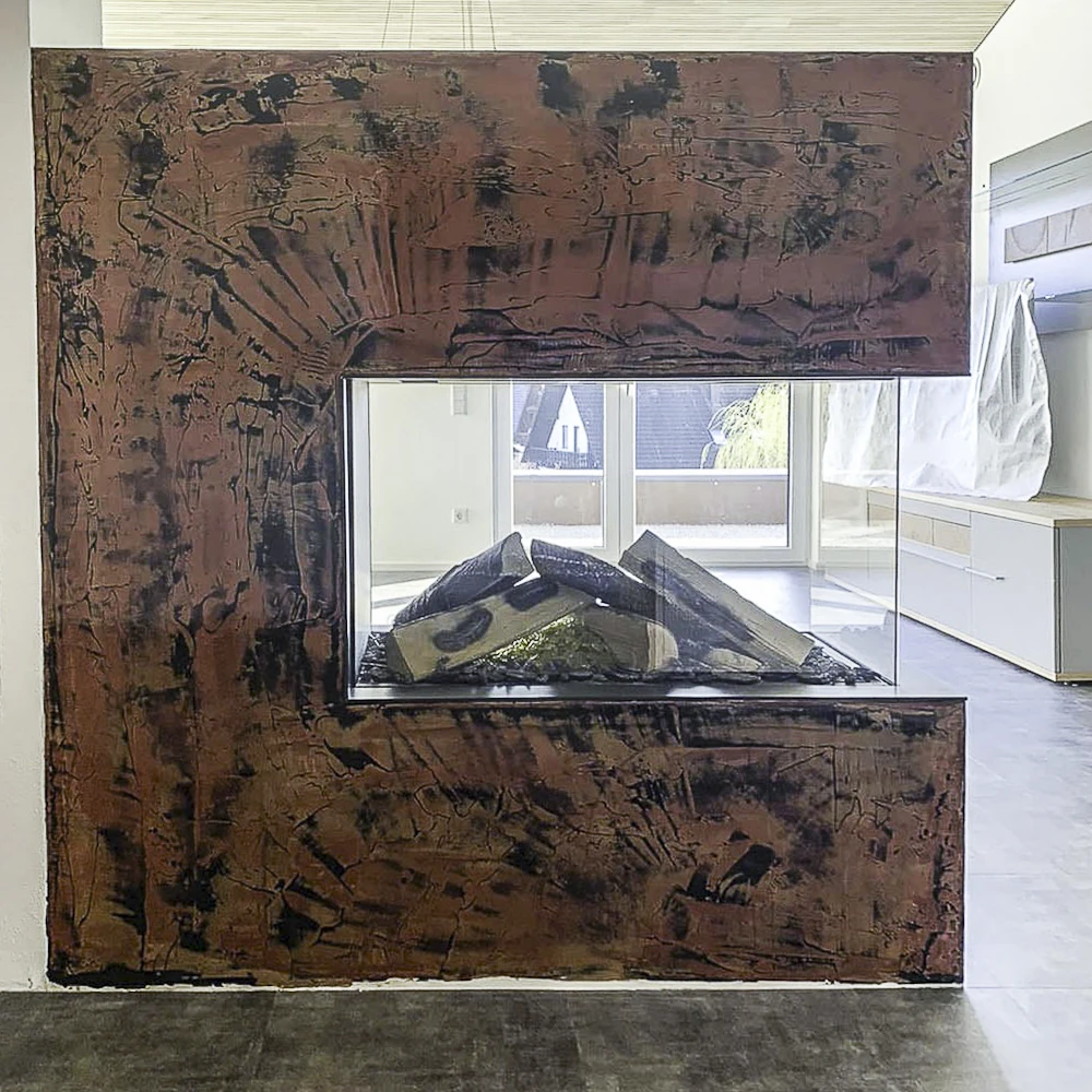 Ein mit Epoxidharz veredelter Kamin in einem Wohnzimmer. Aus der rostbraunen und schwarzen Veredelung ist ein einmaliges Muster entstanden.
