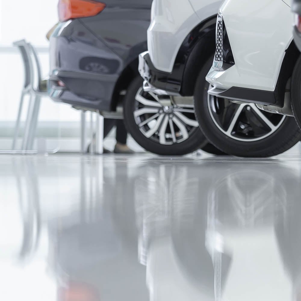 Die veredelte Bodenfläche in einem Autohaus, die so makellos glänzt, dass sich darin die abgestellten Fahrzeuge spiegeln.